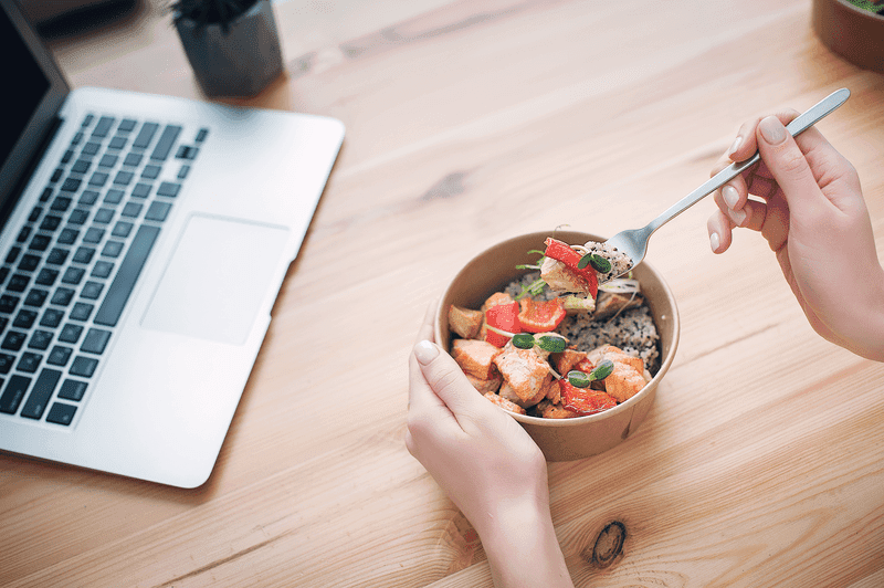 A woman has lunch and works at home. Top view. Space for text in the smartphone